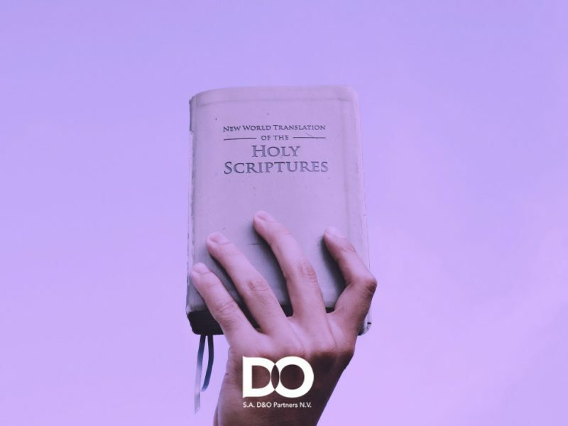 Main tenant fermement une copie de "New World Translation of the Holy Scriptures", avec le logo de la société Xerox D&O Partners affiché en bas.